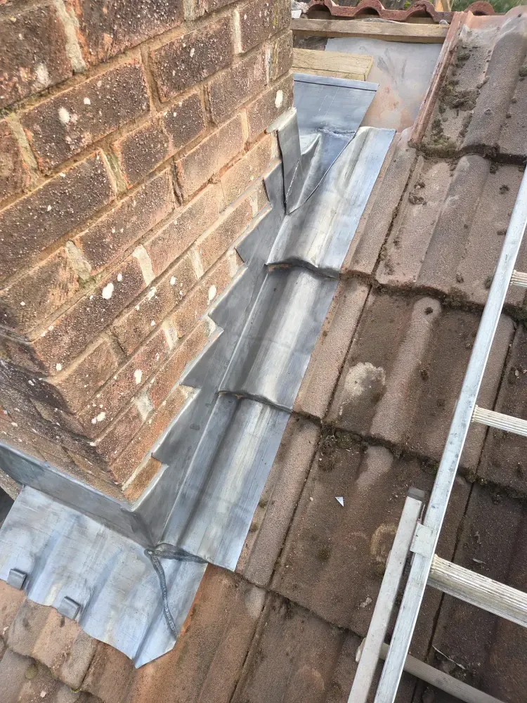 New stepped lead flashing dressed around a brick chimney on a tiled roof