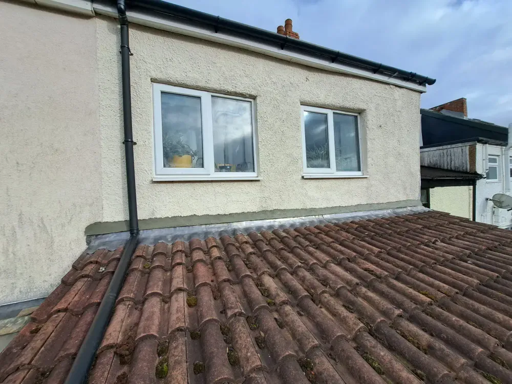 Lead flashing dressed along the abutment where a pantile roof meets a rendered wall